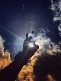 Low angle view of person hand gesturing against sky
