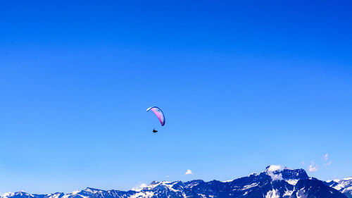 Low angle view of person paragliding against blue sky