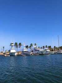 Boats in sea against clear blue sky