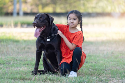 Portrait of woman with dog on field