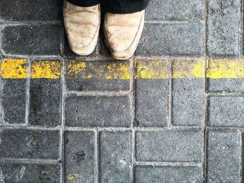 Low section of man standing on cobblestone street