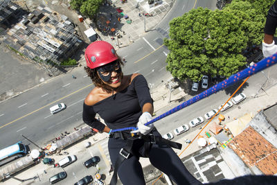 A woman wearing a hero costume with protective helmet walking down a tall rappel building. 