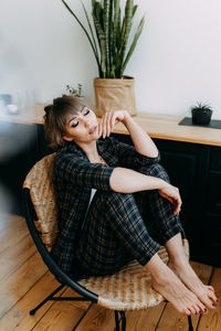 Girl in a business suit and glasses stands working near the window at home, in the office