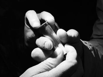 Close-up of man holding hands against black background
