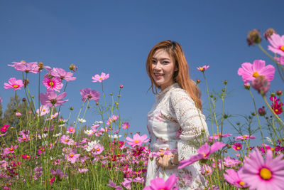 Portrait of smiling woman with pink flowers against plants