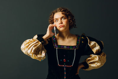 Portrait of young woman drinking water against black background