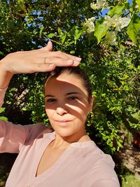 Portrait of smiling young woman standing against trees