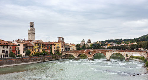 Arch bridge over river against buildings in city