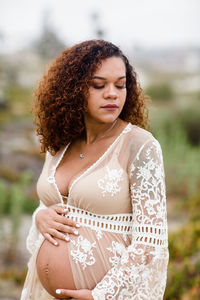 Young pregnant woman posing at beach in sheer dress