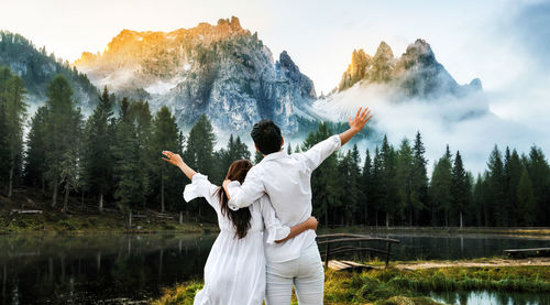 Rear view of person standing by lake against mountain