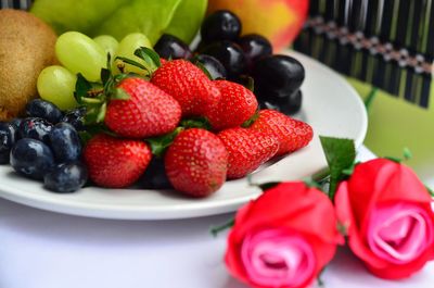 Close-up of fresh fruits in plate with rose on table