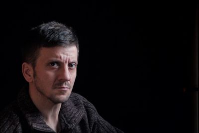 Close-up portrait of mid adult man against black background