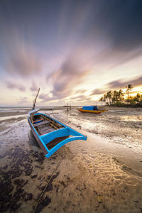 Deck chairs on beach against sky during sunset