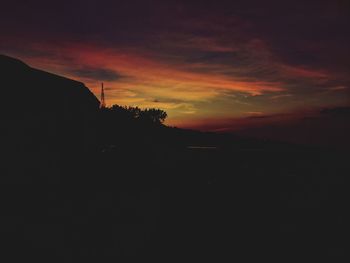 Silhouette landscape against orange sky