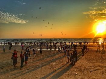 People on beach against sky during sunset