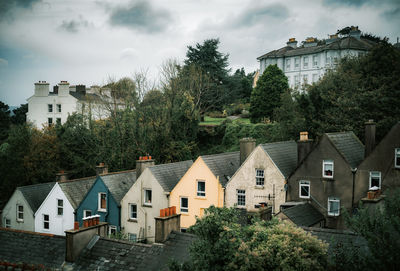 Houses by trees and buildings against sky