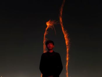 Rear view of man standing against sky at night.