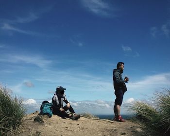 Hikers on cliff against blue sky