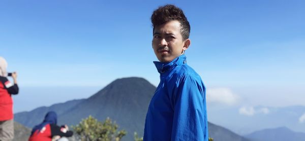 Portrait of young man standing against blue sky