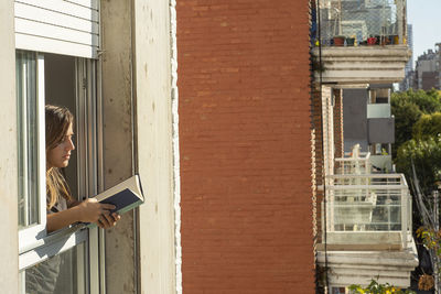 Woman in the windows during quarantine reading a book