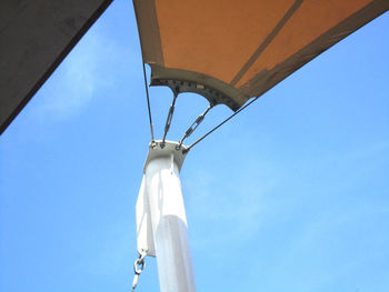 Low angle view of telephone pole against clear blue sky