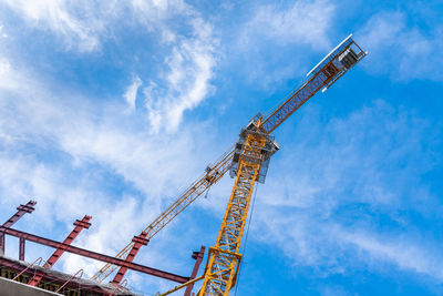 View of the tower crane cabin from below. blue sky with light white clouds.