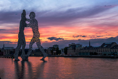 Silhouette of city at riverbank during sunset