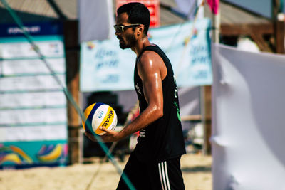 Young man holding ball while standing outdoors