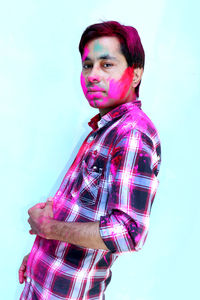 Portrait of young man standing against blue background
