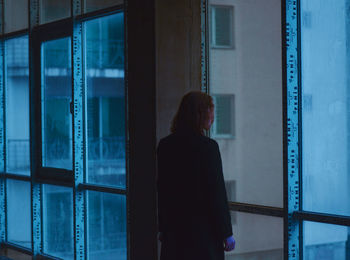 Rear view of woman looking through window