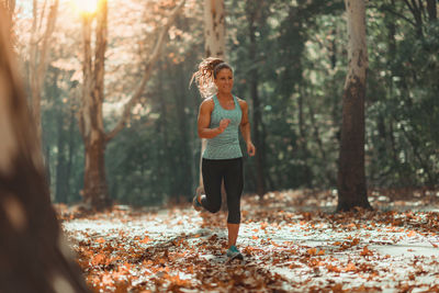 Full length of woman with arms raised in forest