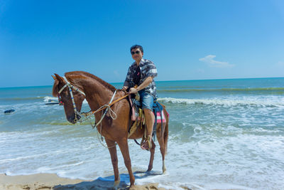 Portrait of man riding horse at beach