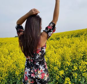 Midsection of woman standing by yellow flowers on field