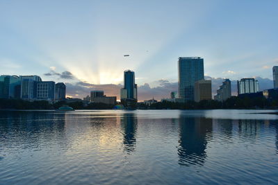 Buildings by river against sky in city