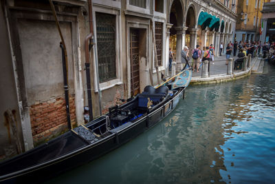 People on boat in canal along buildings