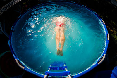 High angle view of shirtless man swimming in wading pool