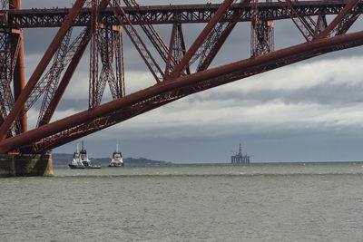 Two ships and an oilrig under a bridge near edinburgh