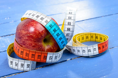 Close-up of tape measure and apple on wooden table