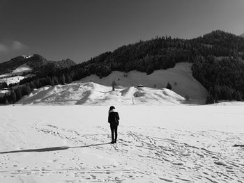 Rear view of person walking on snow covered mountain