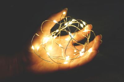 Cropped hand holding illuminated lights in darkroom