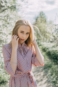 Portrait of young woman standing against trees