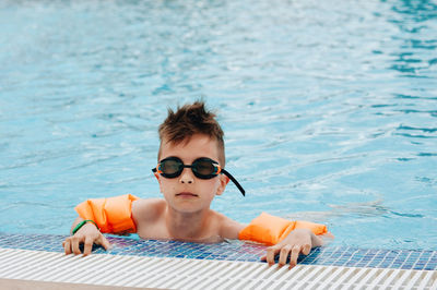 Portrait of boy wearing swimming goggles in pool