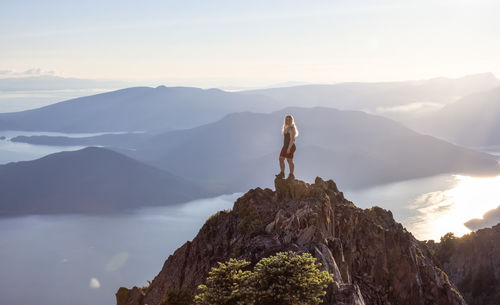 Man standing on rock against sky