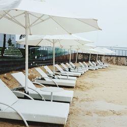 Empty white lounge chairs with umbrellas at beach