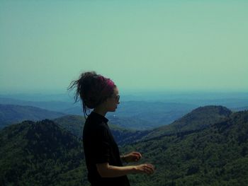 Side view of man standing on mountain against sky