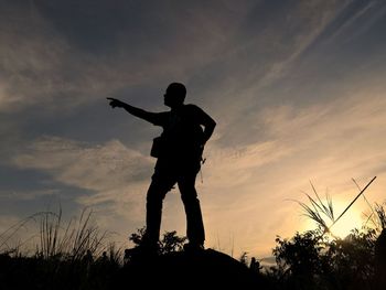 Silhouette man standing by tree against sky during sunset