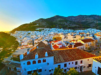 High angle view of townscape and mountains against blue sky