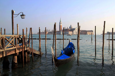 Wooden posts in lake against sky