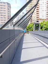 Man walking on bridge amidst buildings in city