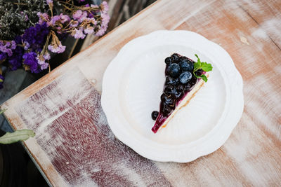 A piece of blueberry cheesecake on wooden table.